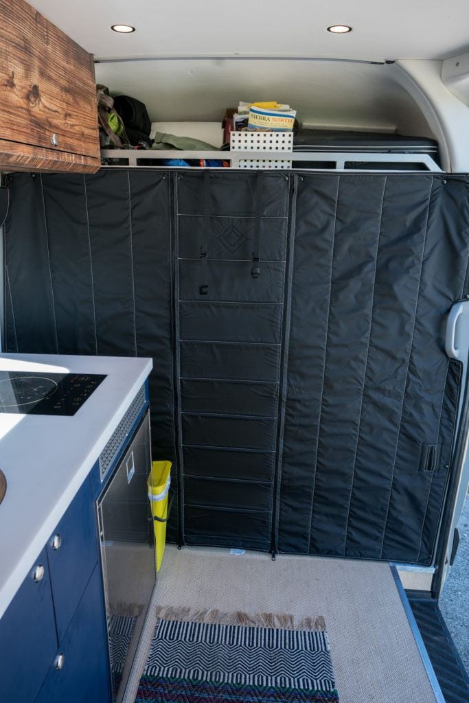 Black curtain separating back of converted camper van to cab