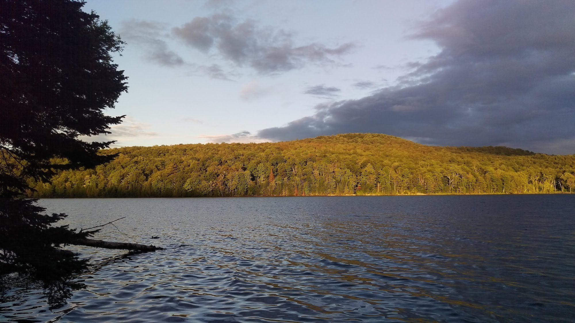 Light from setting sun on Green River Reservoir forest and lake in Vermont