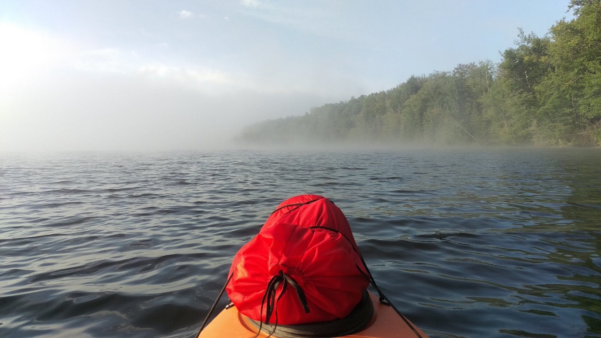 Bow of kayak on lake with gear strapped to the top