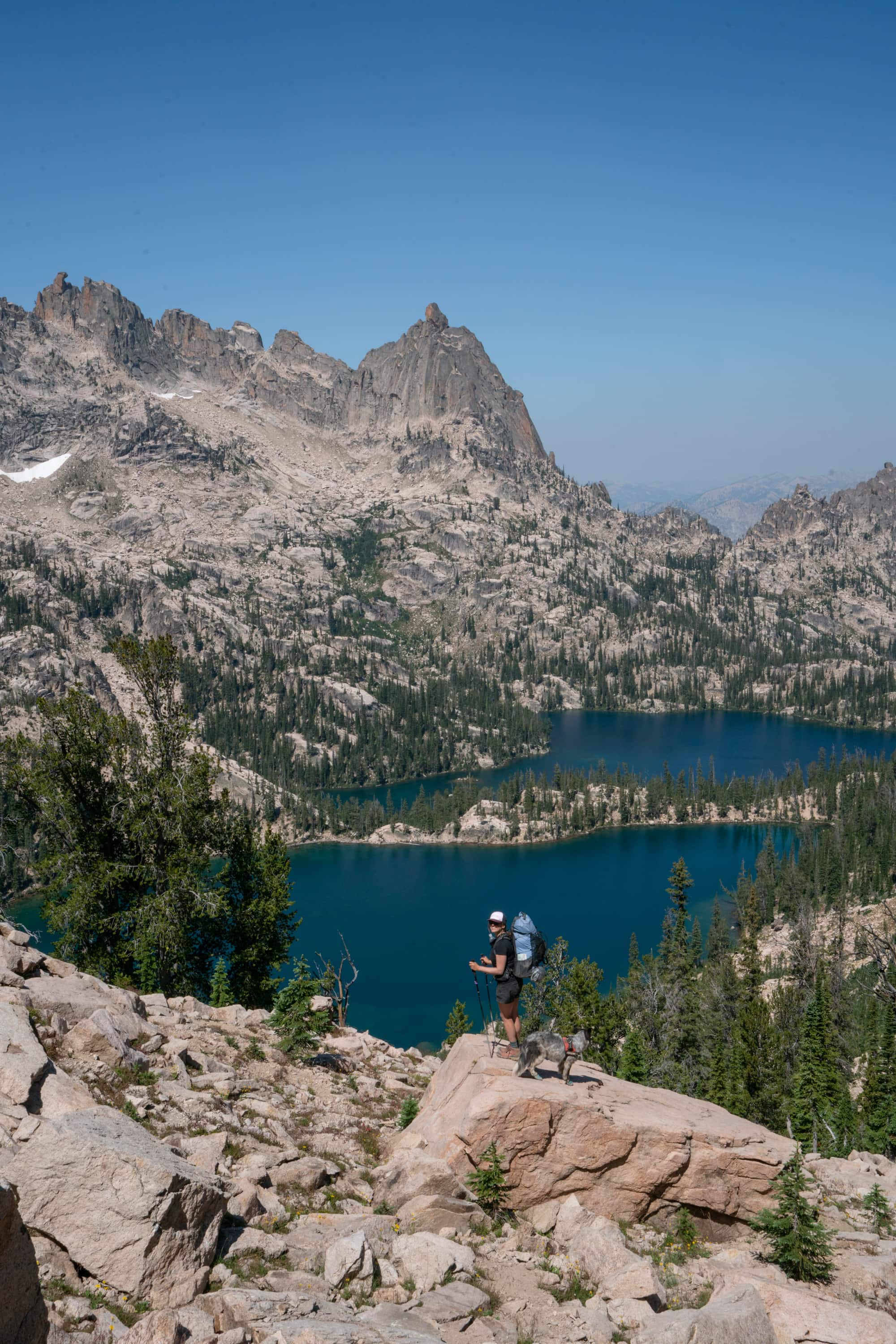 Female backpacker standing on a rock overlook with beautiful views of Baron Lakes in the Sawtooth Mountain Wilderness in Idaho