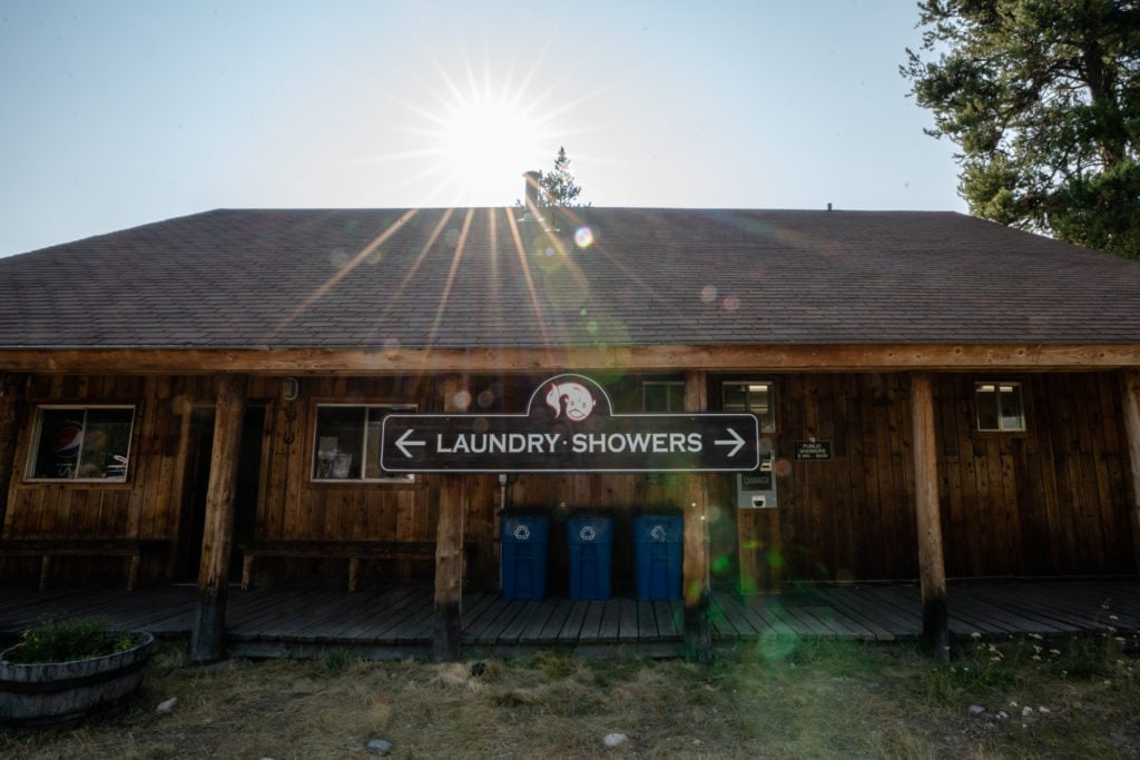 Front porch of wooden building with sign that says "Laundry - Showers" with arrows pointing opposite directions