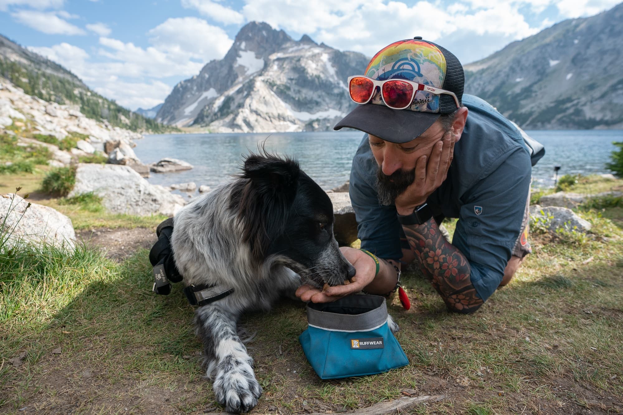 Man feeding dog from his palm in a meadow next to Sawtooth Lake in Idaho