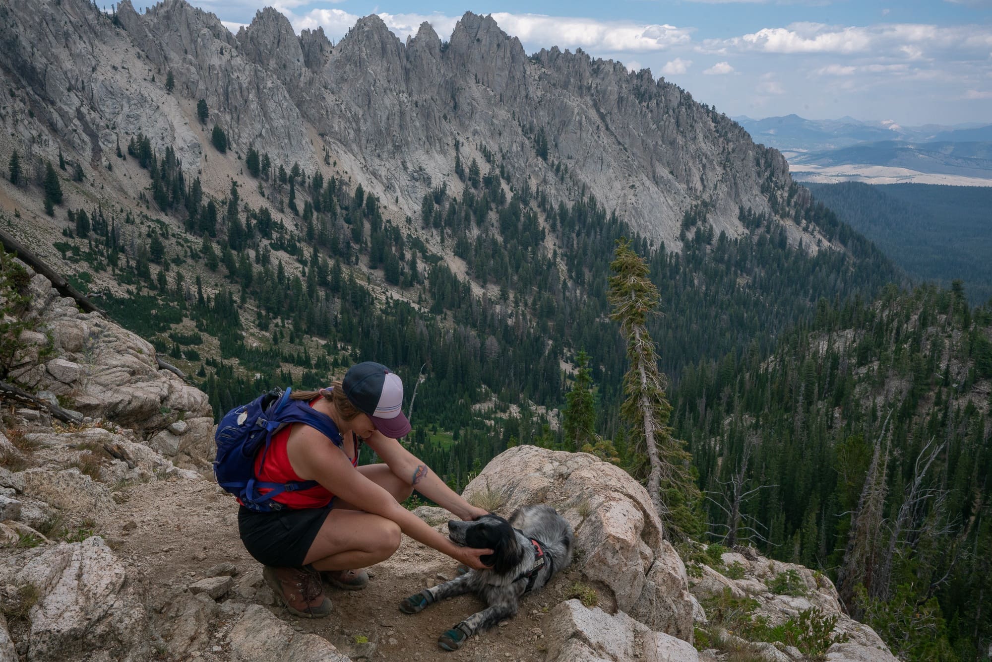 Woman kneeling next to dog at beautiful Sawtooth Wilderness overlook