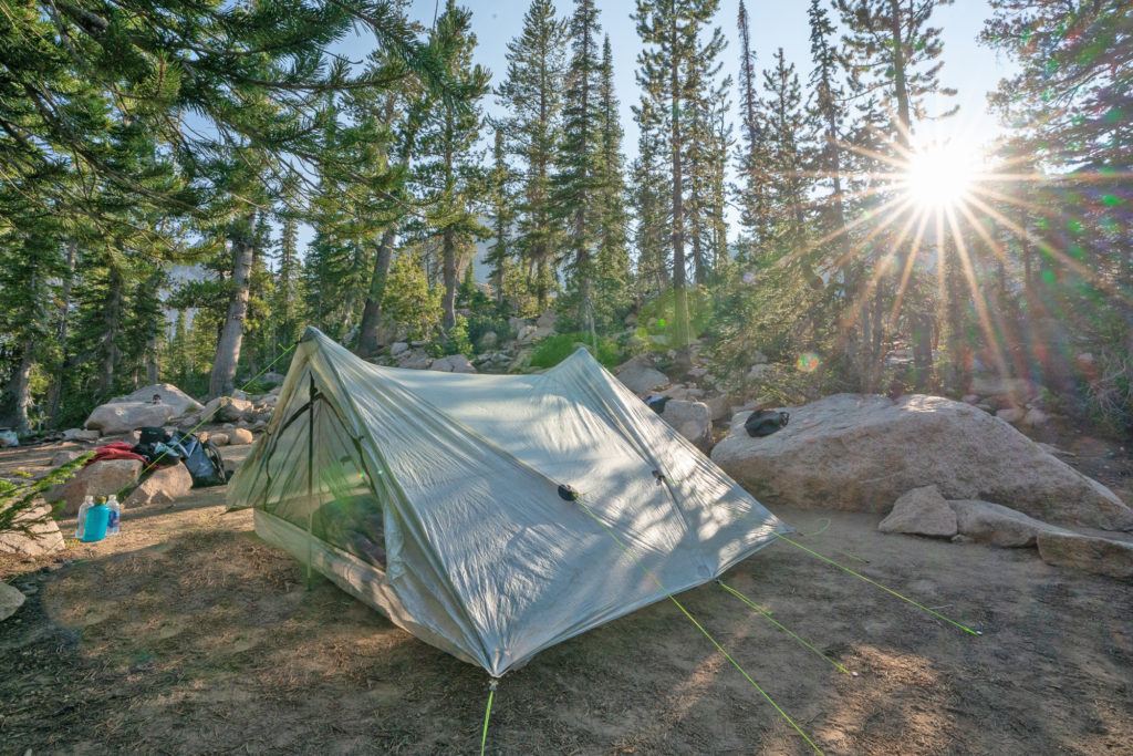 Ultralight Zpacks tent set up at remote campground in the forest with sun shining through the trees