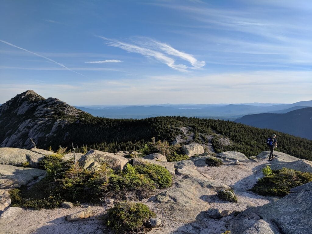 HIker on rock slabs at the summit of Mt. Chocorua in the White Mountains of New Hampshire