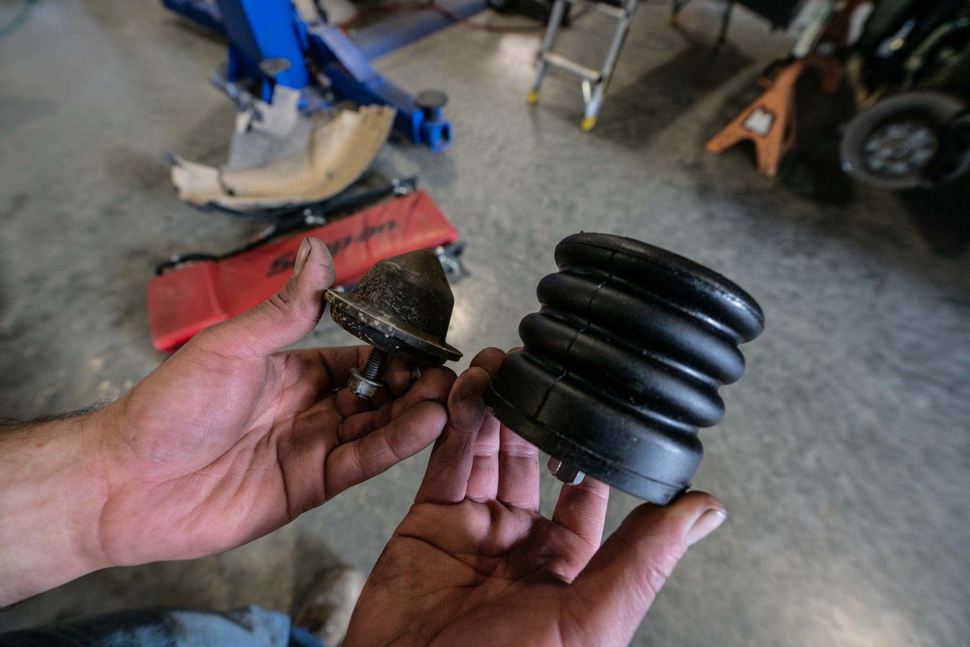 Person holding factory bump stop in left hand and upgraded sumo spring in right hand for better Sprinter van suspension