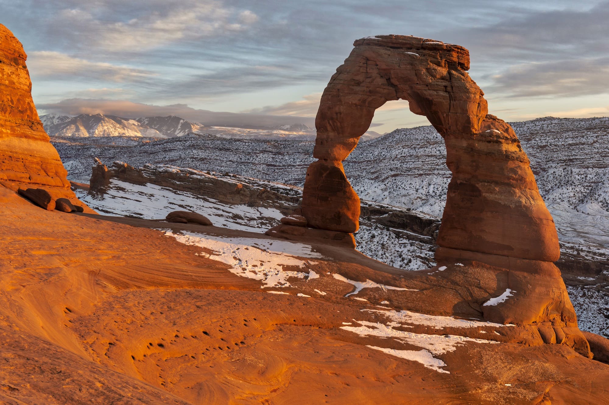 Red rock arch in Arches National Park with dusting of snow covering landscape