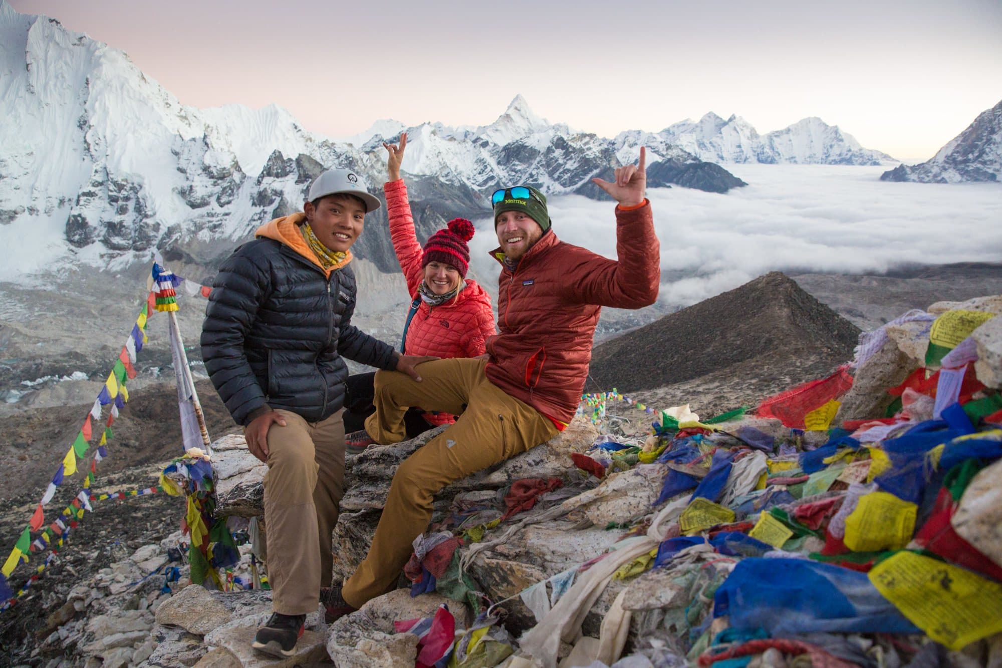 Three people posing for photo at summit of mountain in Nepal