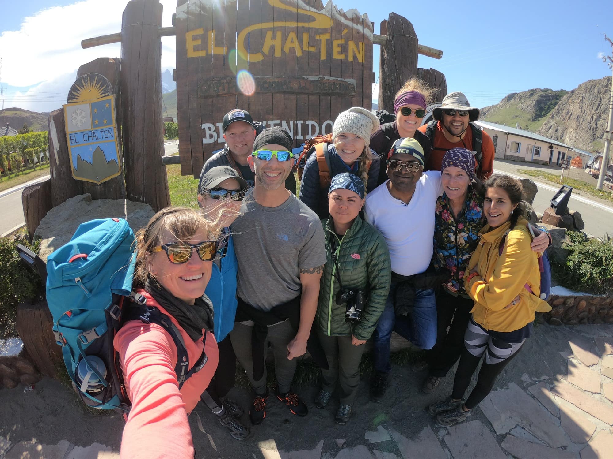 Group of hikers taking a selfie in front of a wooden sign that says El Chaltén