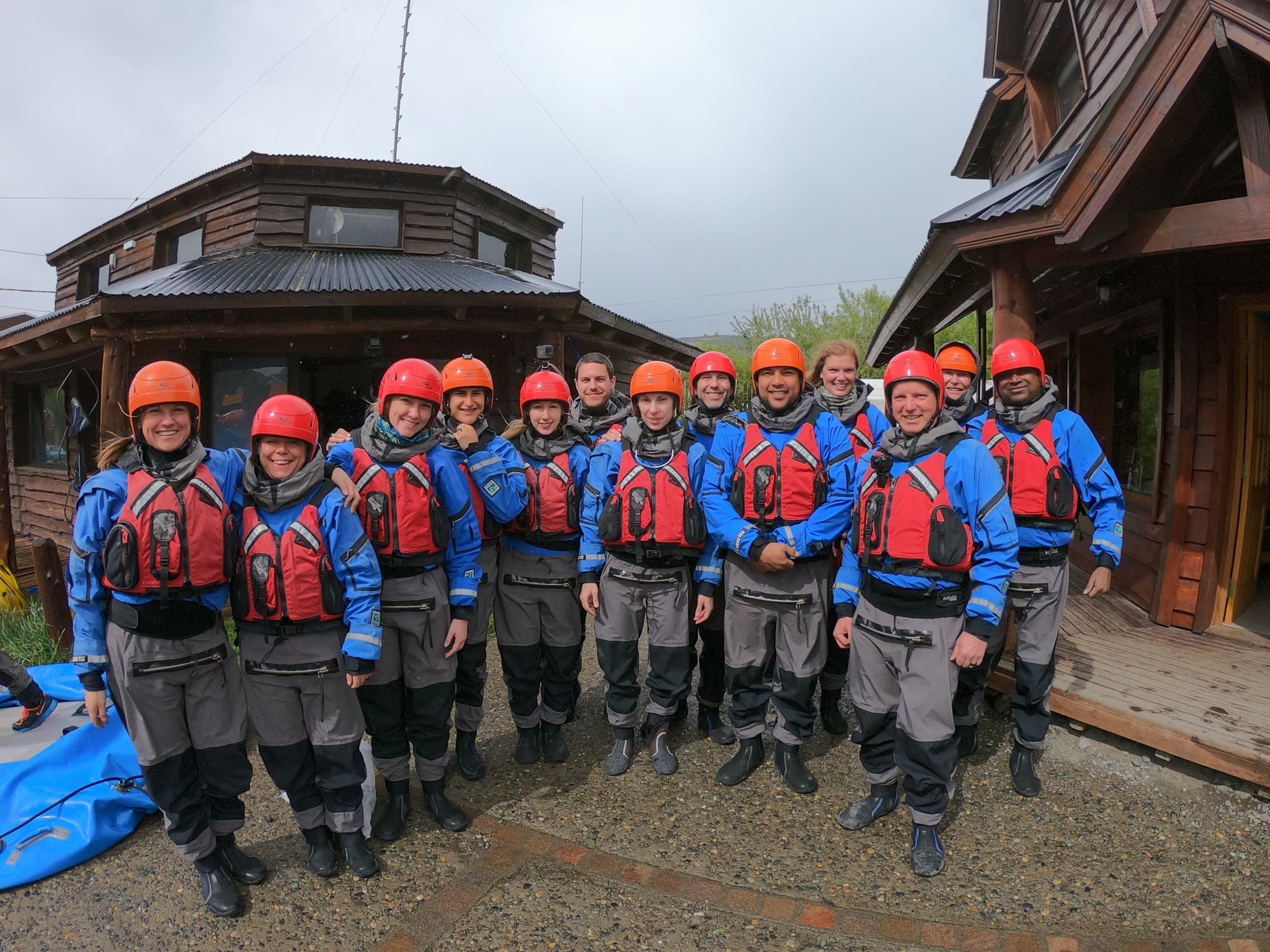 Large group geared up with life jackets, helmets and wet suits in preparation of a white water rafting trip