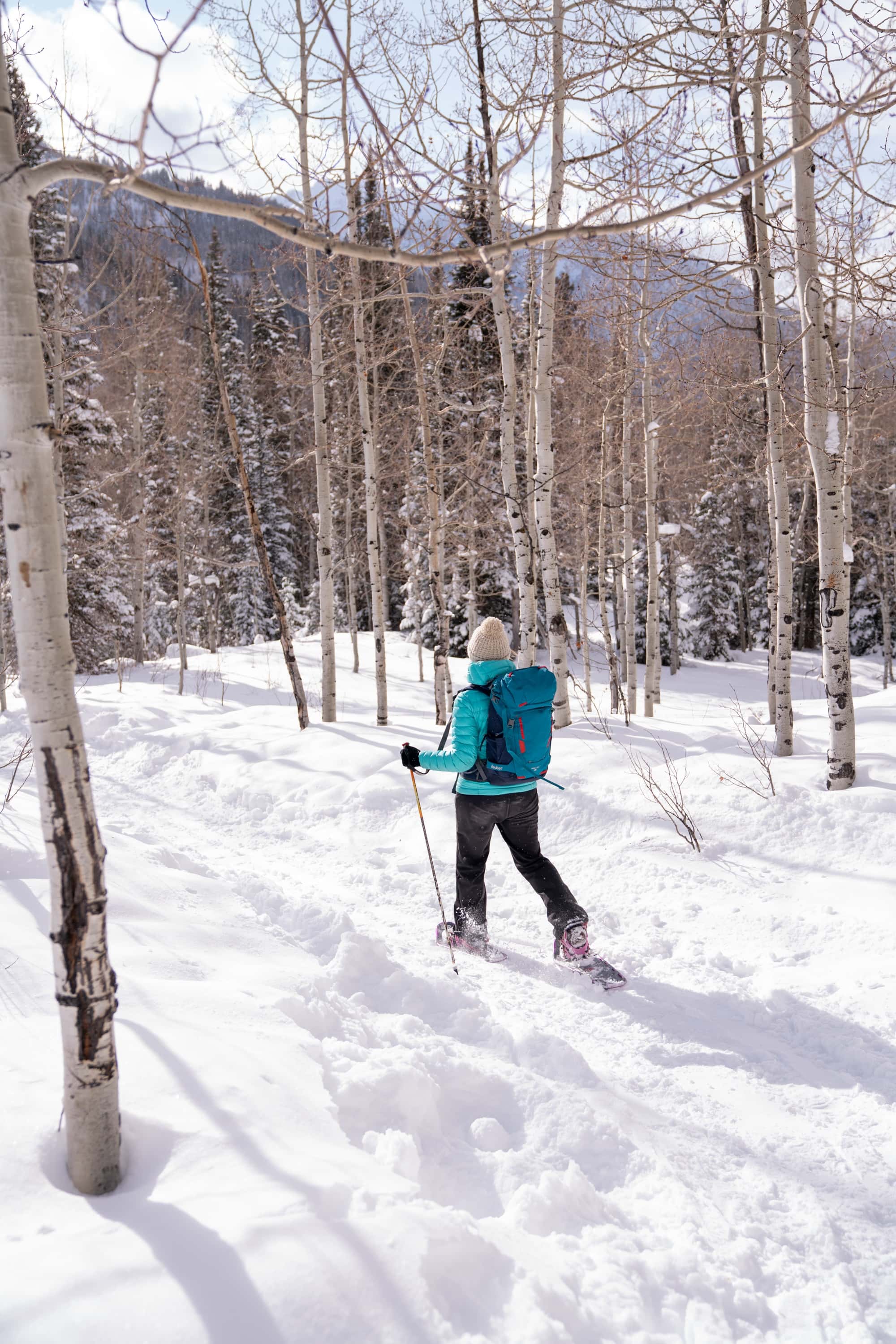 A close up of a woman snowshoeing on a flat path in the winter