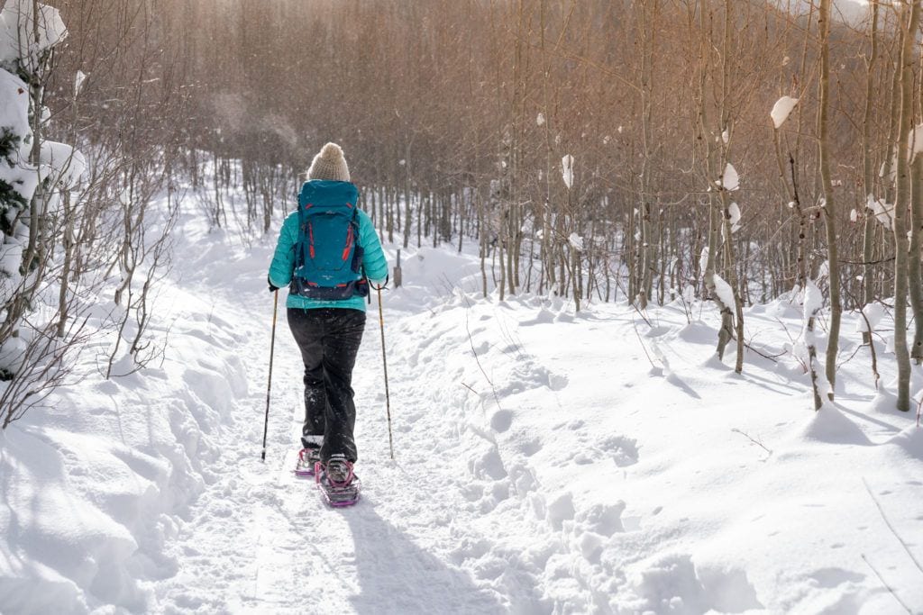 Woman snowshoeing on snowy trail through the woods