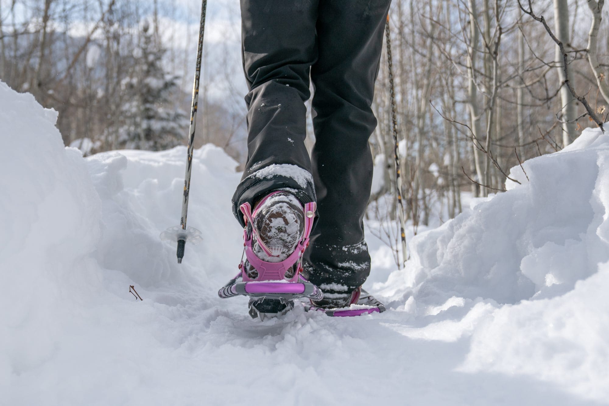 A closeup of someone wearing Yukon Charlie's Advanced Float snowshoes on a snowy path