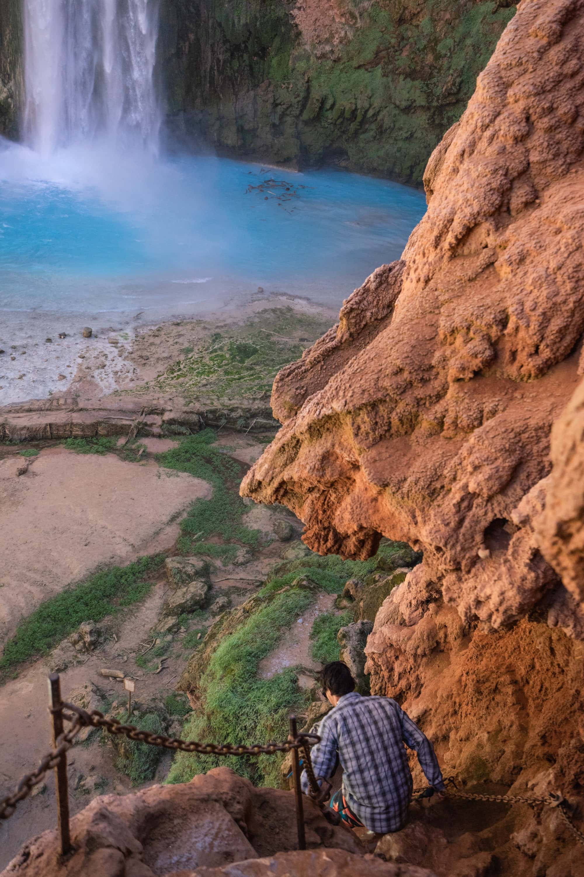 Man hiking down steep and technical rock trail to the base of Mooney Falls in Havasu Canyon, Arizona