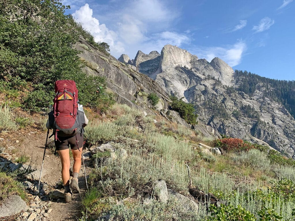 A woman carries a red backpacking pack with an attached Kula cloth pee rag in Sequoia National Park