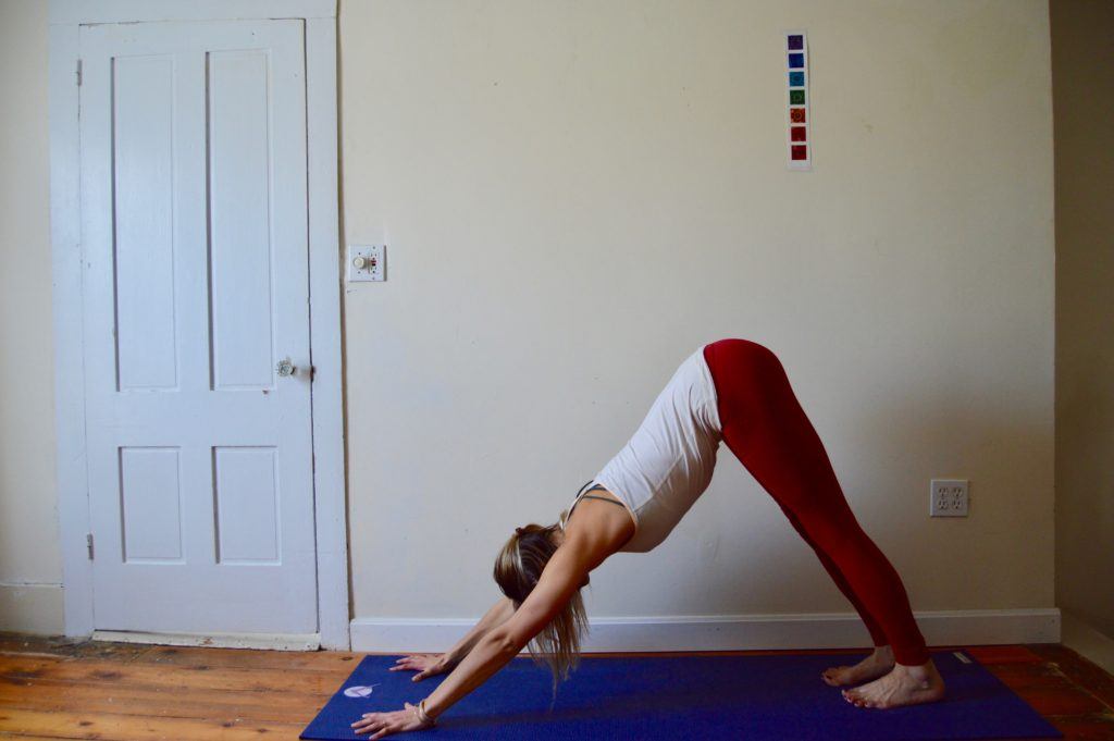 woman doing downward dog yoga post on mat