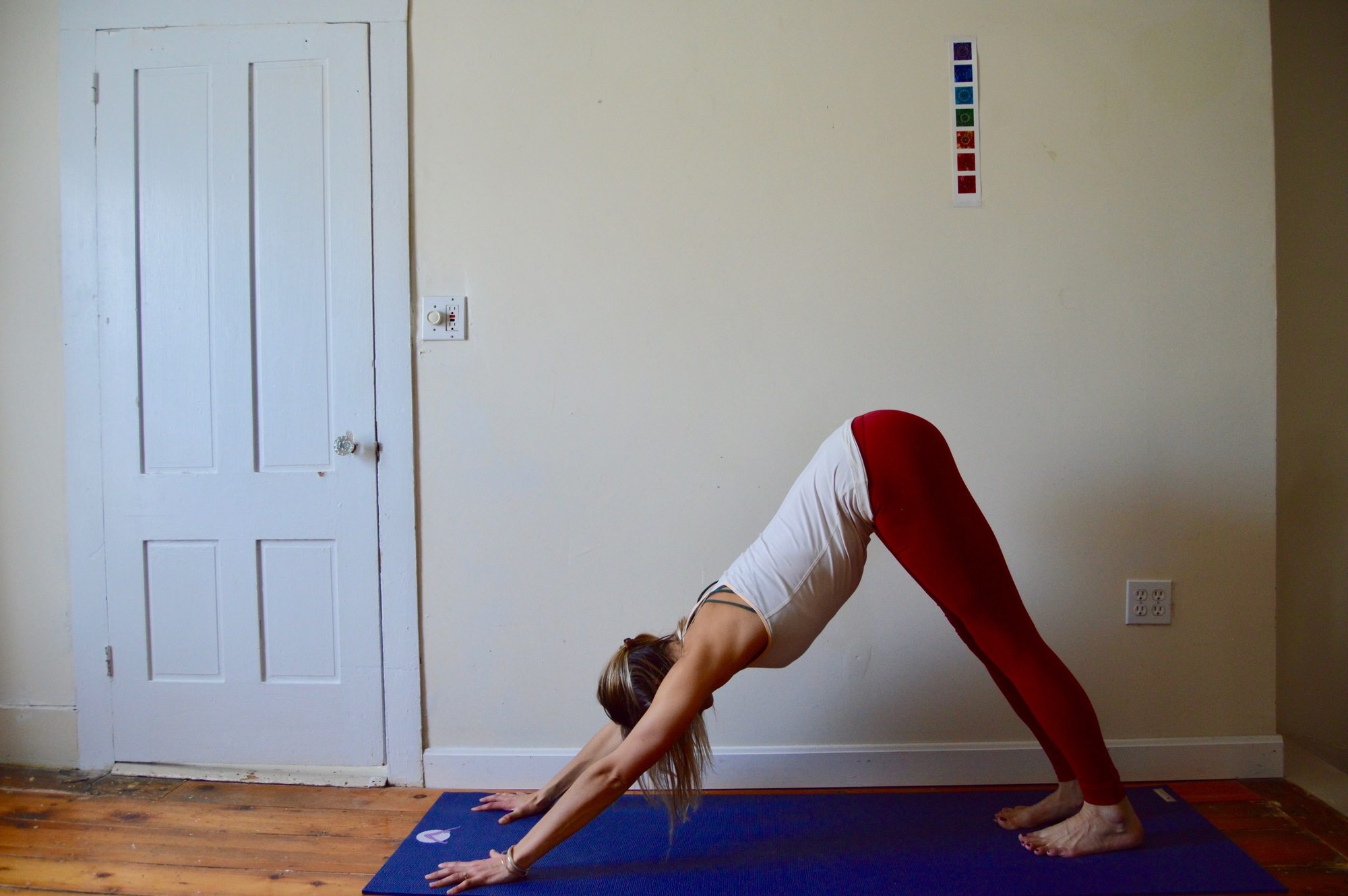 Woman holding downward facing dog at home // learn the best yoga poses for skiers