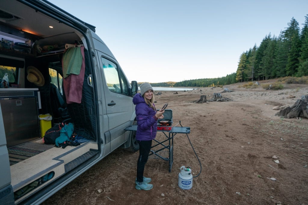 A woman stands outside with her camping stove on a small table