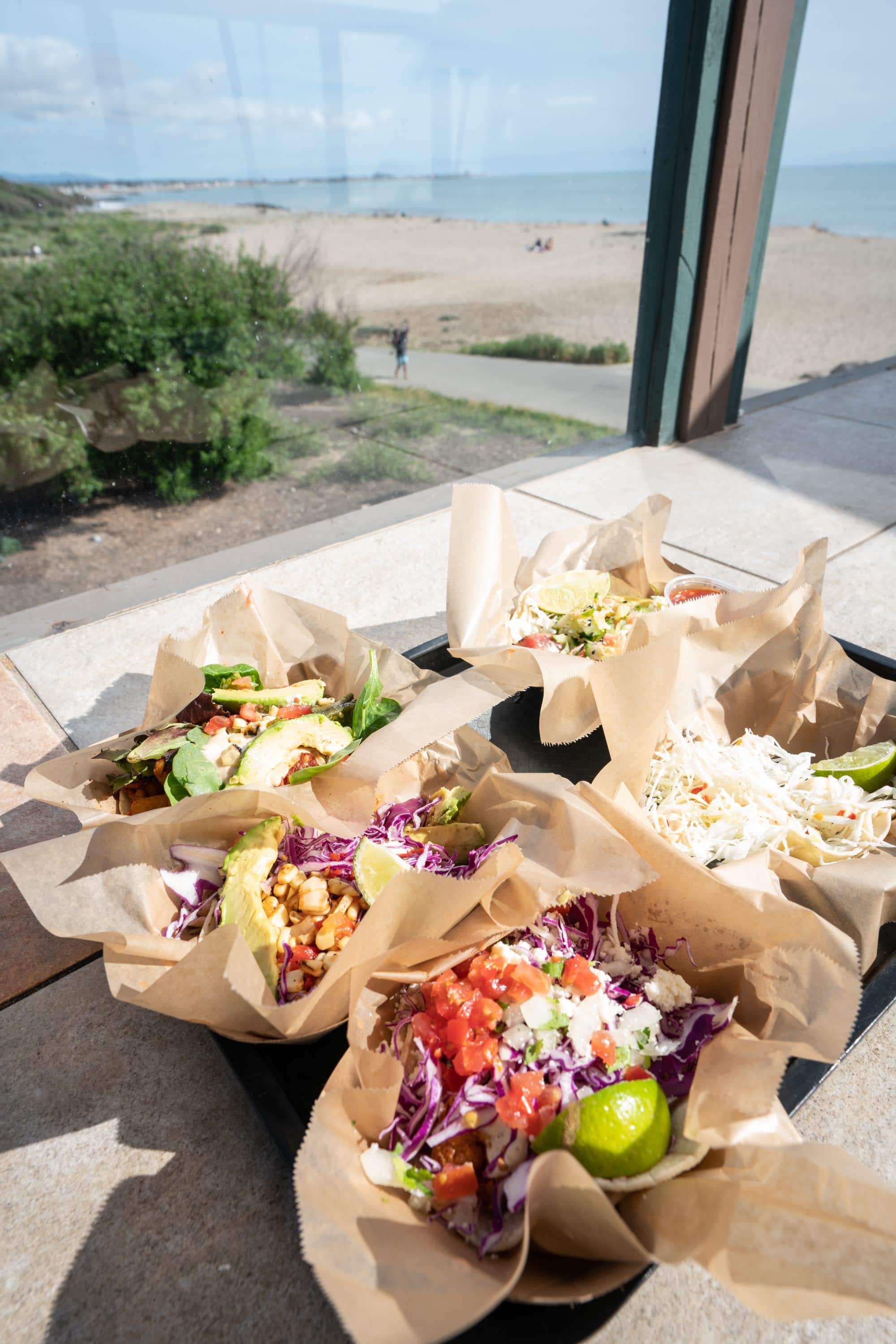 Platter of fresh tacos on counter with window looking out onto Ventura Waterfront in Callifornia