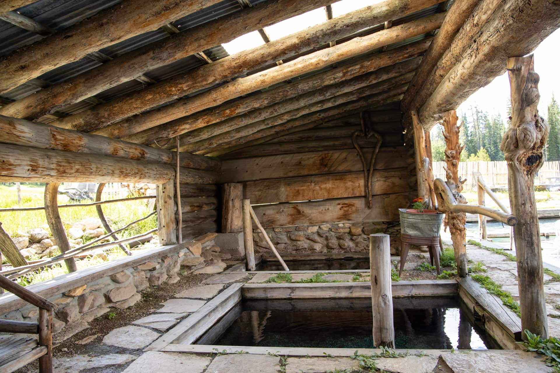 Square in-ground natural pool under log cabin lean-to at Burgdorf hot springs resort in Idaho