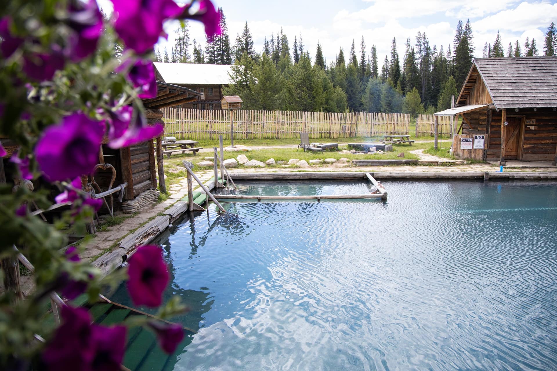 Natural hot springs pool at Burgdorf Hot Springs in Idaho with historic wooden buildings 