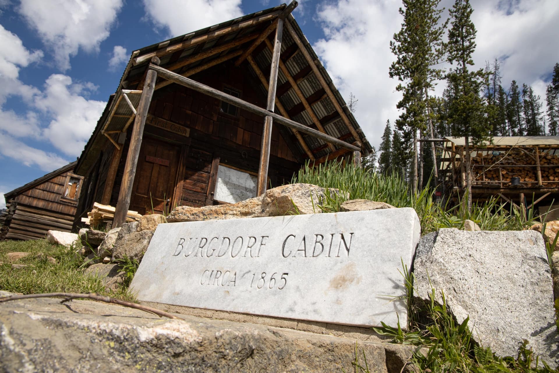 Historic wooden cabin at Burgdorf Hot Springs in Idaho with plaque that says "Burgdorf Cabin Circa 1865" in front.