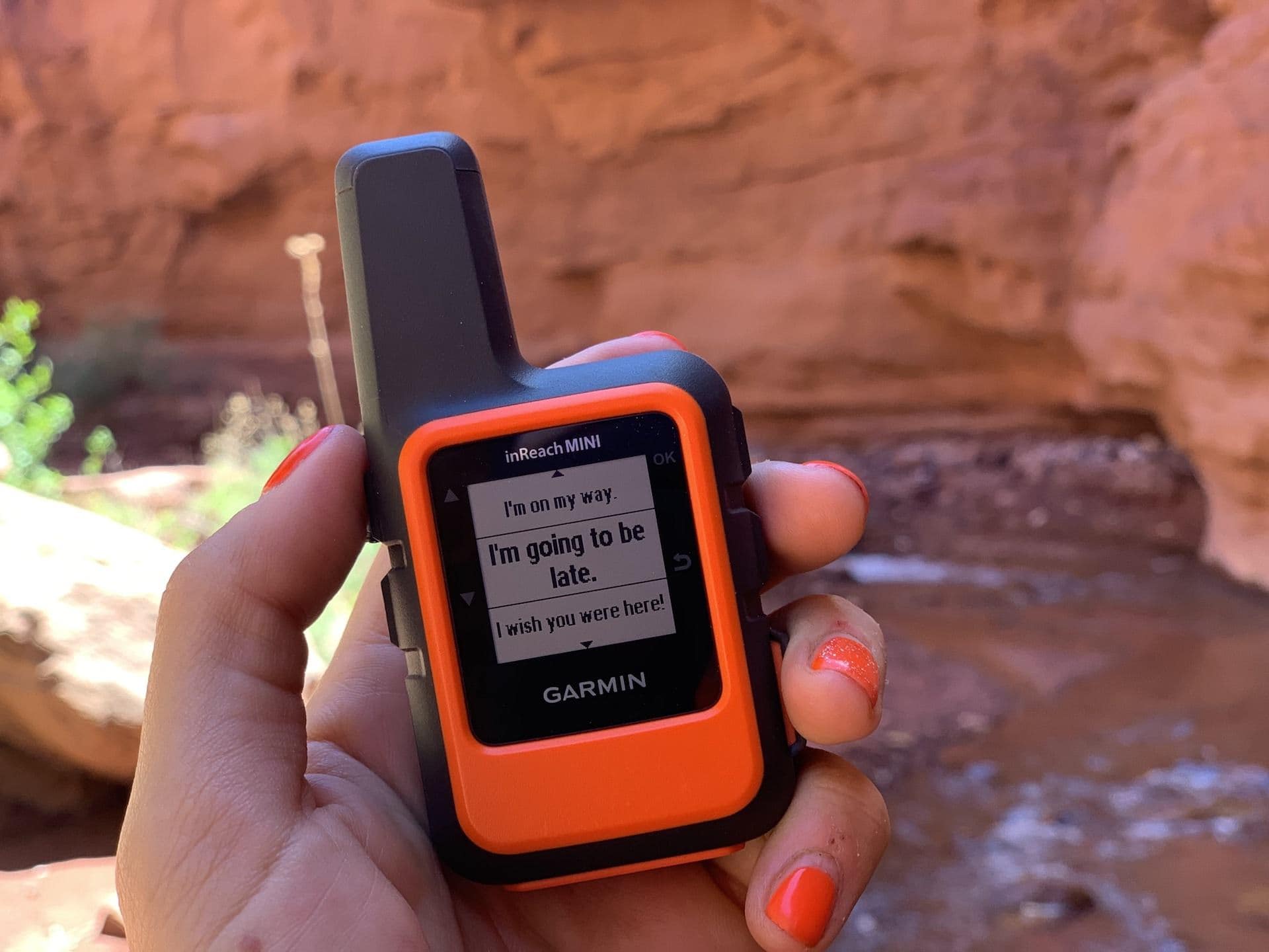 Up-close photo of hand holding Garmin inReach Mini GPS satellite communicator