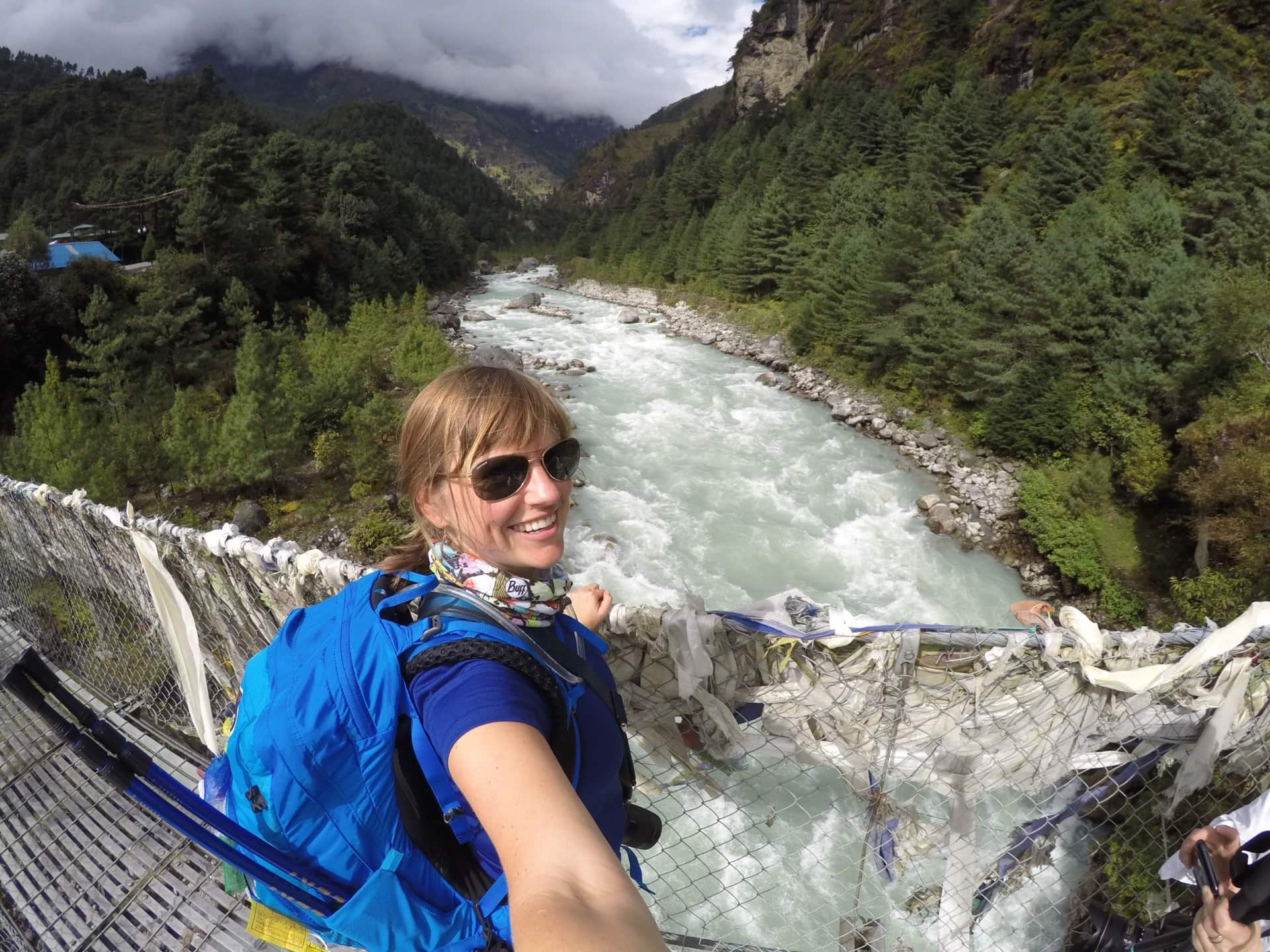 A woman looks over a river while standing on a bridge in Nepal