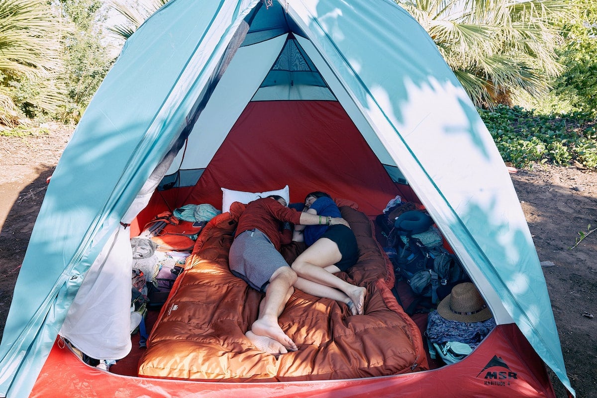 A man and woman lay inside the MSR Habitude 4P camping tent