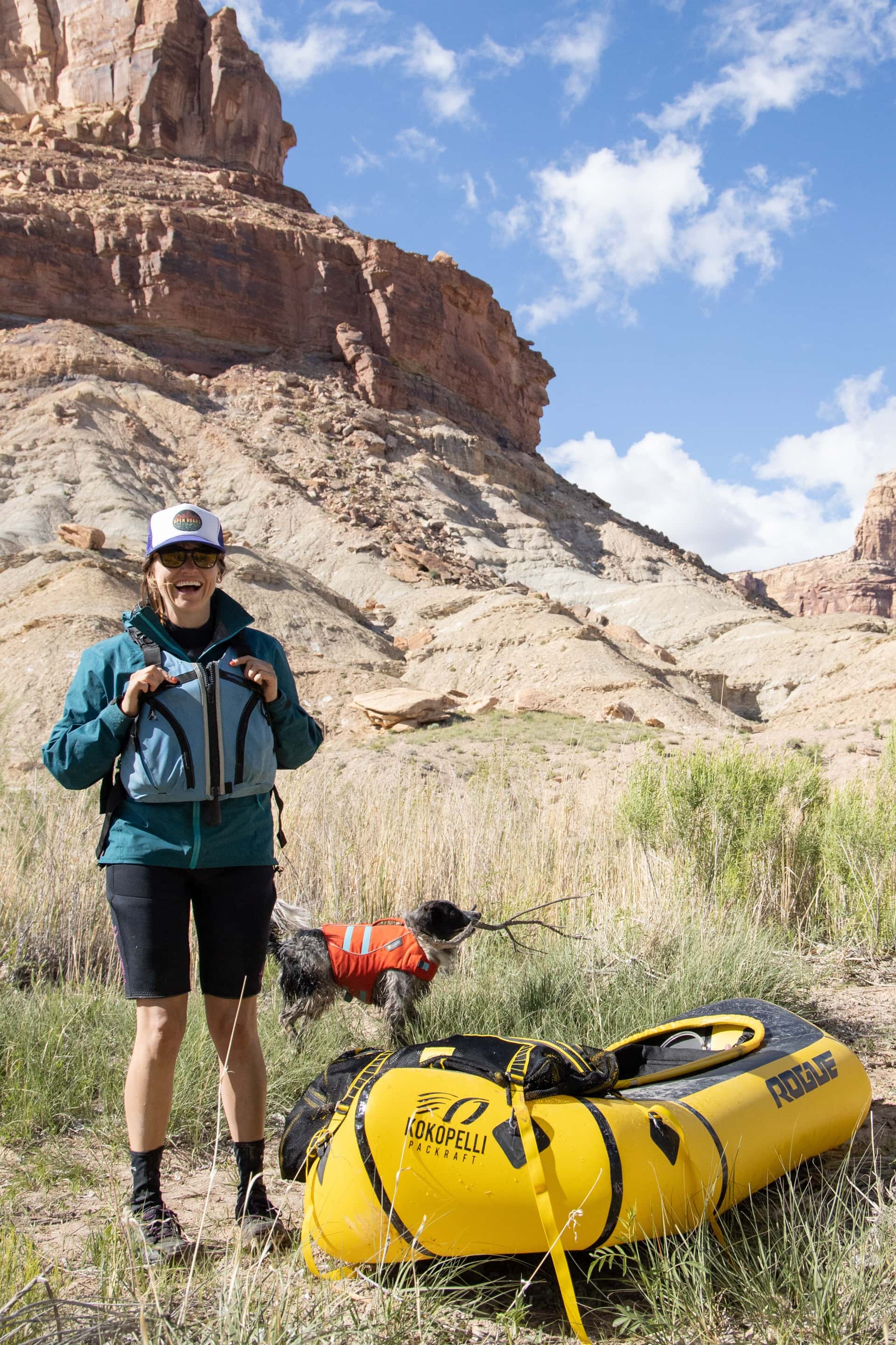 Kristen standing on shore next to Kokopelli packraft ready to float down the San Rafael River in Utah