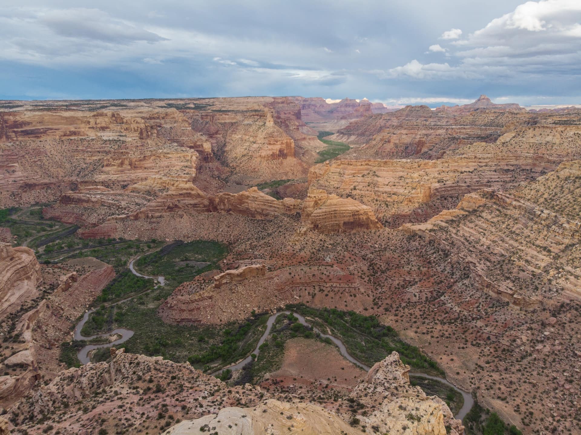 Top down views of the green San Rafael river basin winding through the red rock bluffs of the San Rafael Swell in Utah.