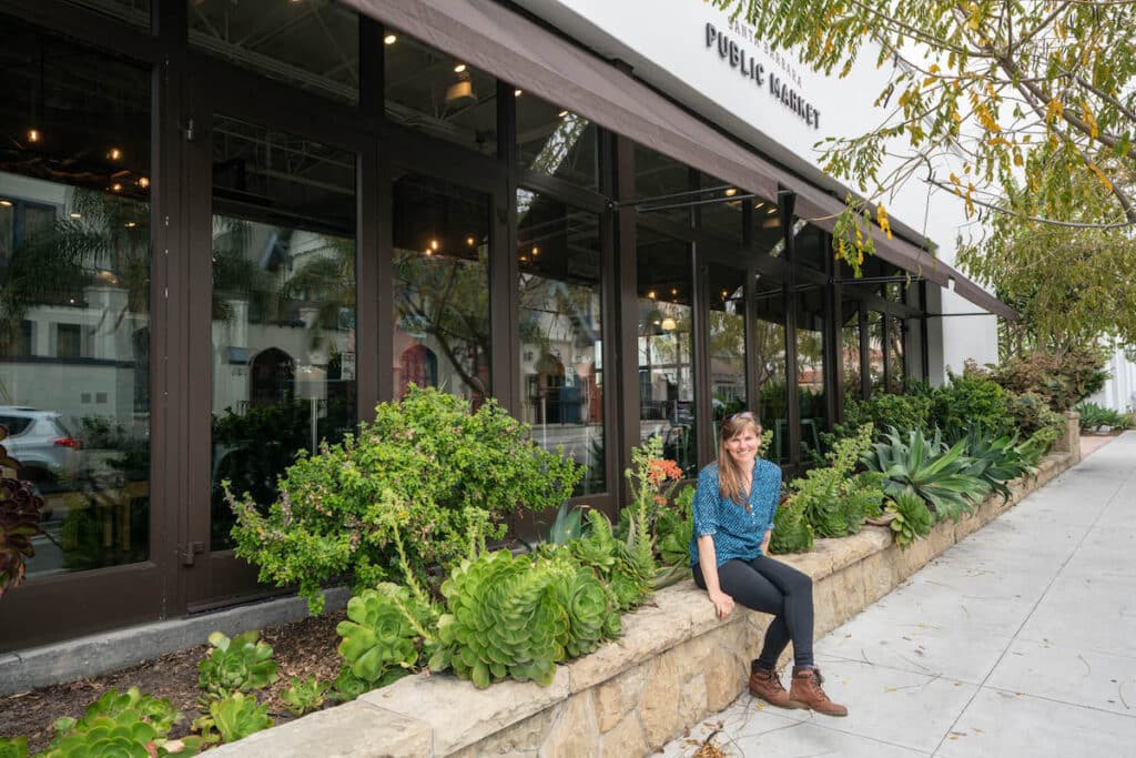 Woman sitting on stone retainer outside Santa Barbara's Public Market in California