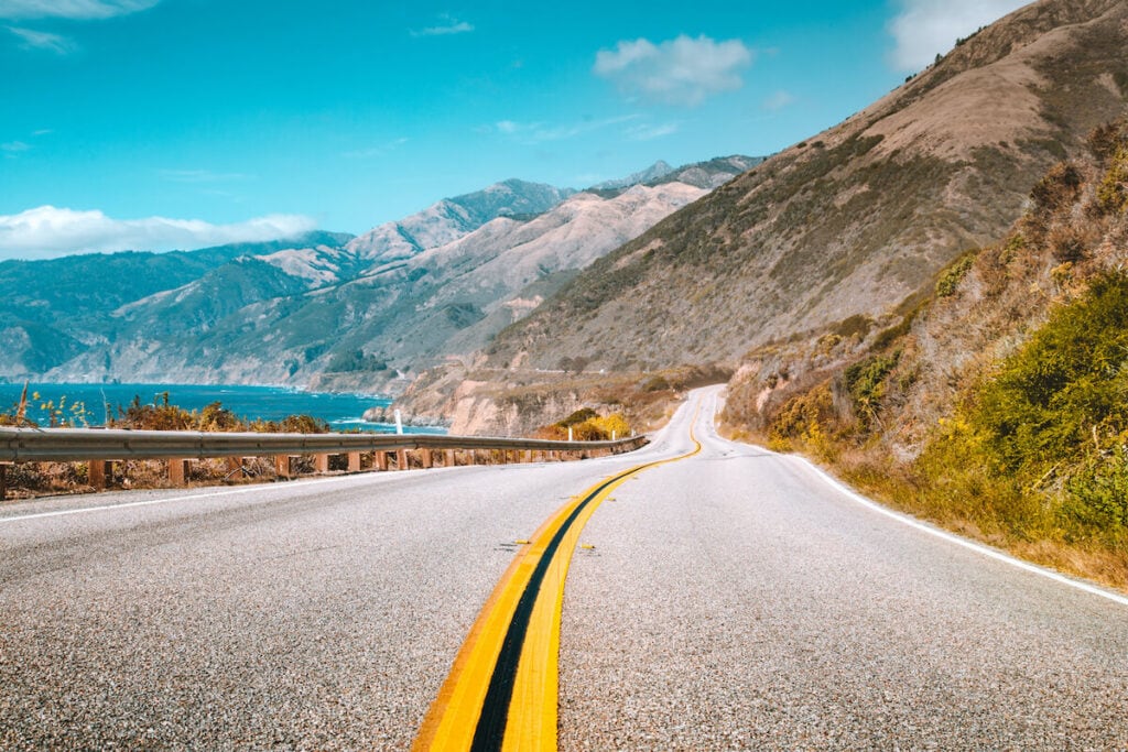 Highway 1 with jagged coastal mountains and the ocean on a sunny day