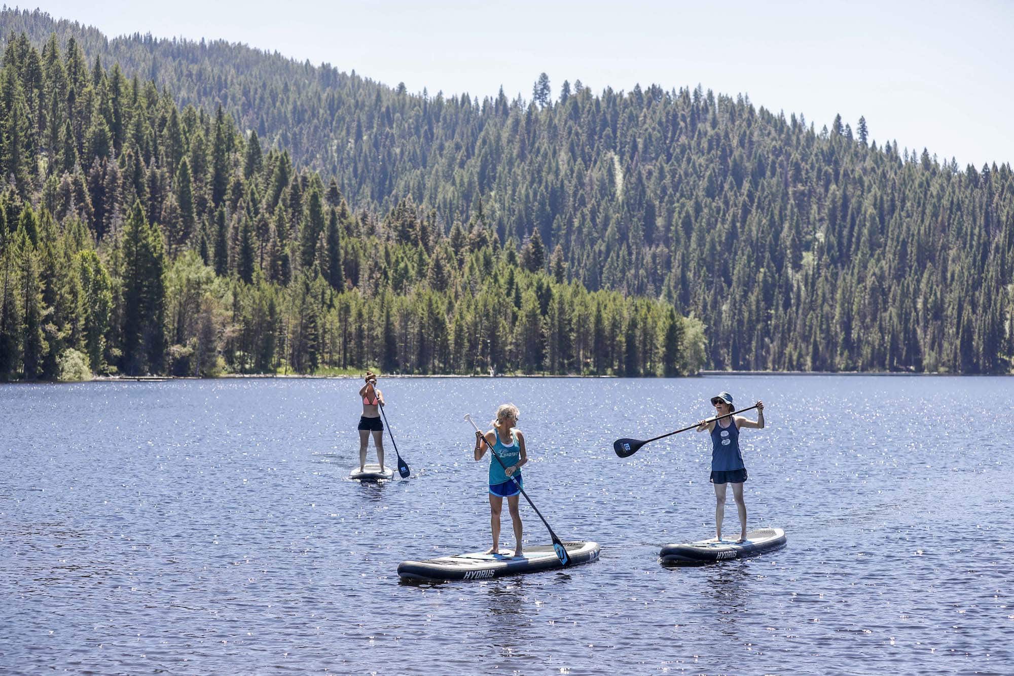 Three women paddleboarding on Jug Mountain Ranch's reservoir at Open Roads Fest 