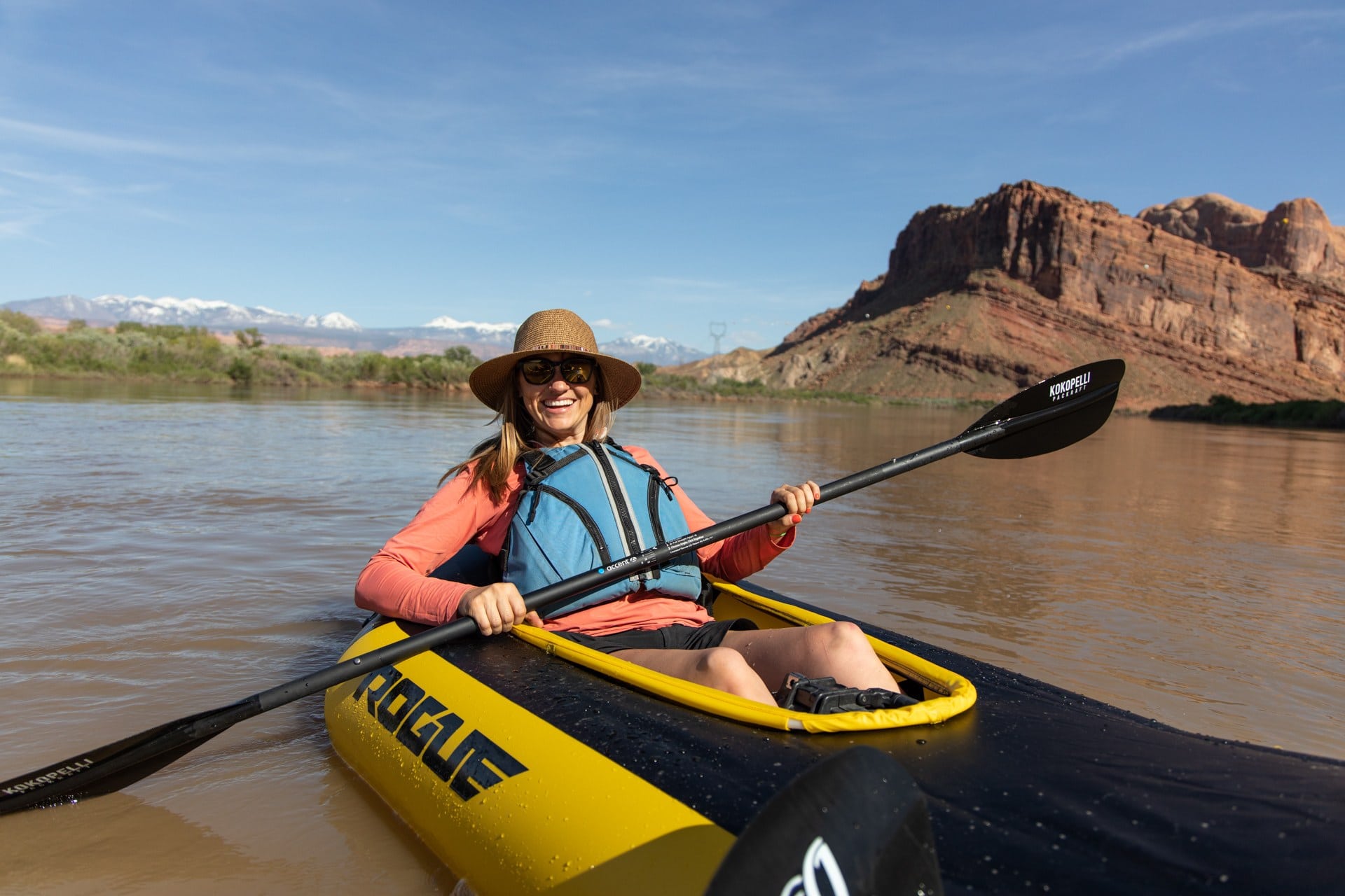 A woman paddling wearing Wallaroo Sedona Hat & Carve Designs Cruz Rashguard