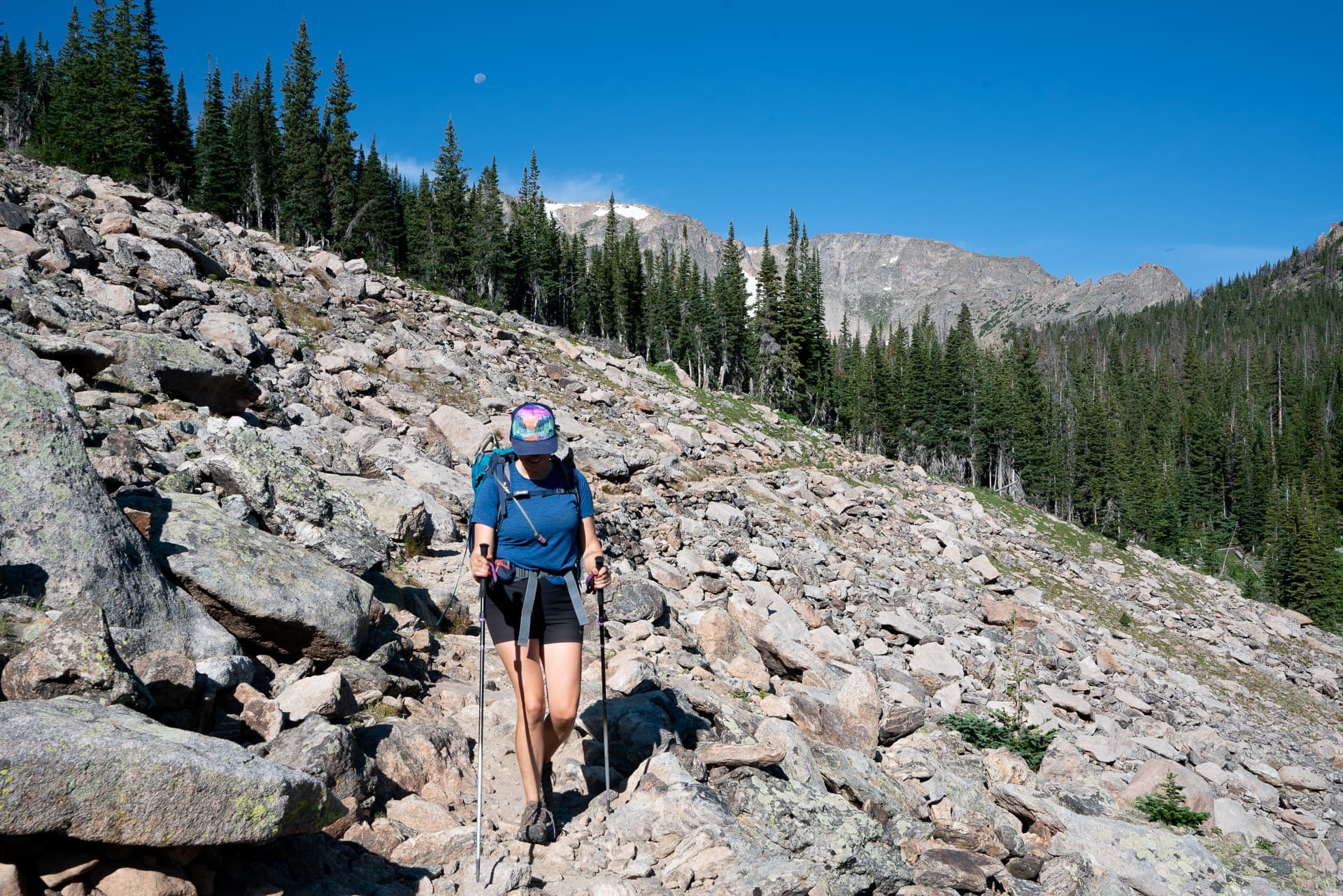 Kristen hiking on rocky trail with hiking gear and trekking poles