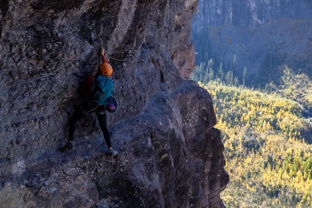 Climber traversing narrow ledge on via ferrata route in Colorado