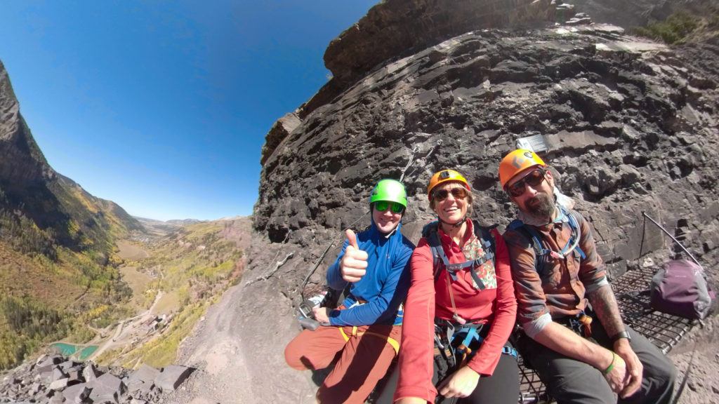 Three climbers smiling for photo while on the via ferrata climbing route in Telluride