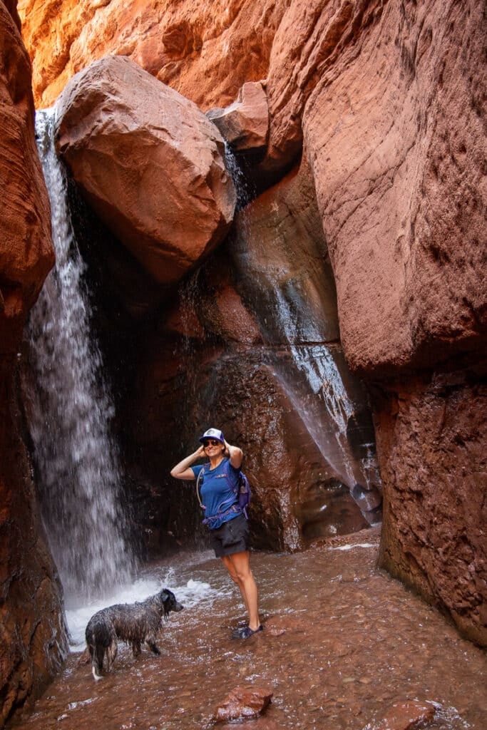 Woman with dog standing under Mary Jane Falls in Moab Utah