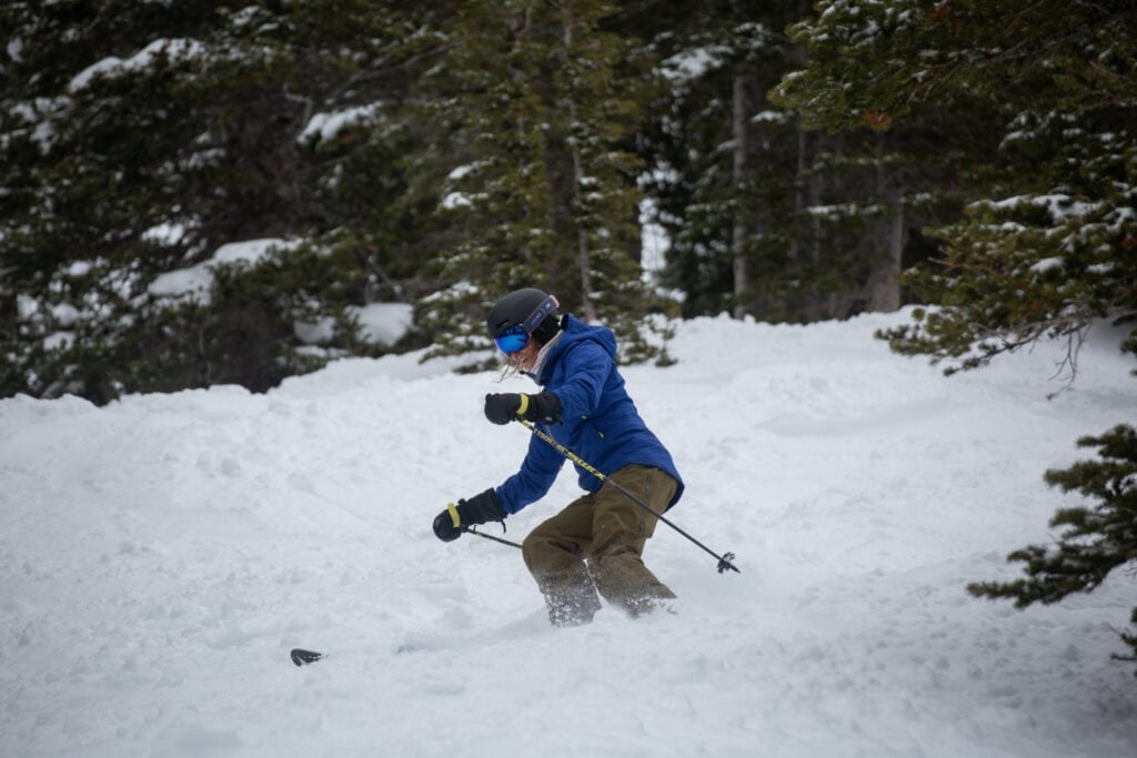 Woman skiing down mountain in glad of evergreen trees