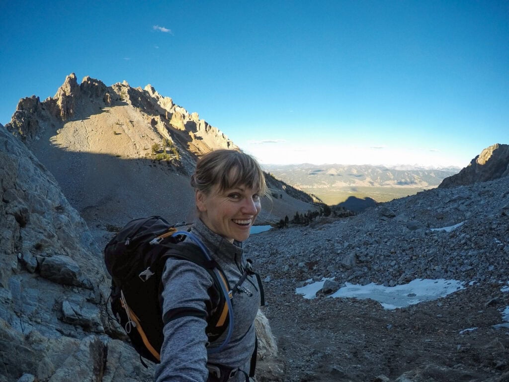 Hiker with backpack exploring rugged mountain landscape at sunrise.