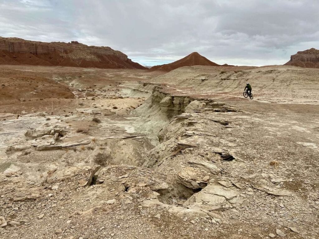 Mountain biker on singletrack trail surrounded by barren desert terrain in Goblin Valley State Park, Utah