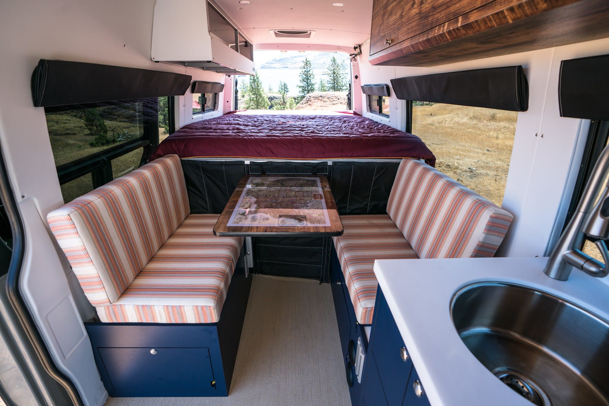 the interior of a campervan with two bench seats facing each other and a fixed bed