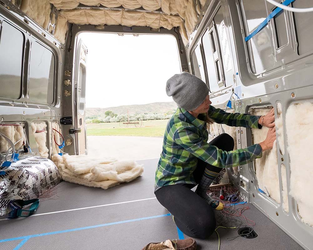 Woman installing Havelock wool as van insulation in DIY van build