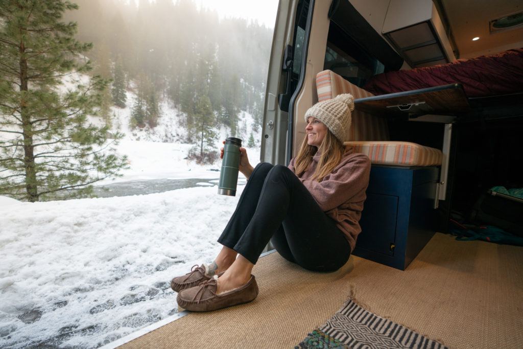 Kristen sitting on the floor of her second Sprinter van showing the high-density vinyl weave flooring