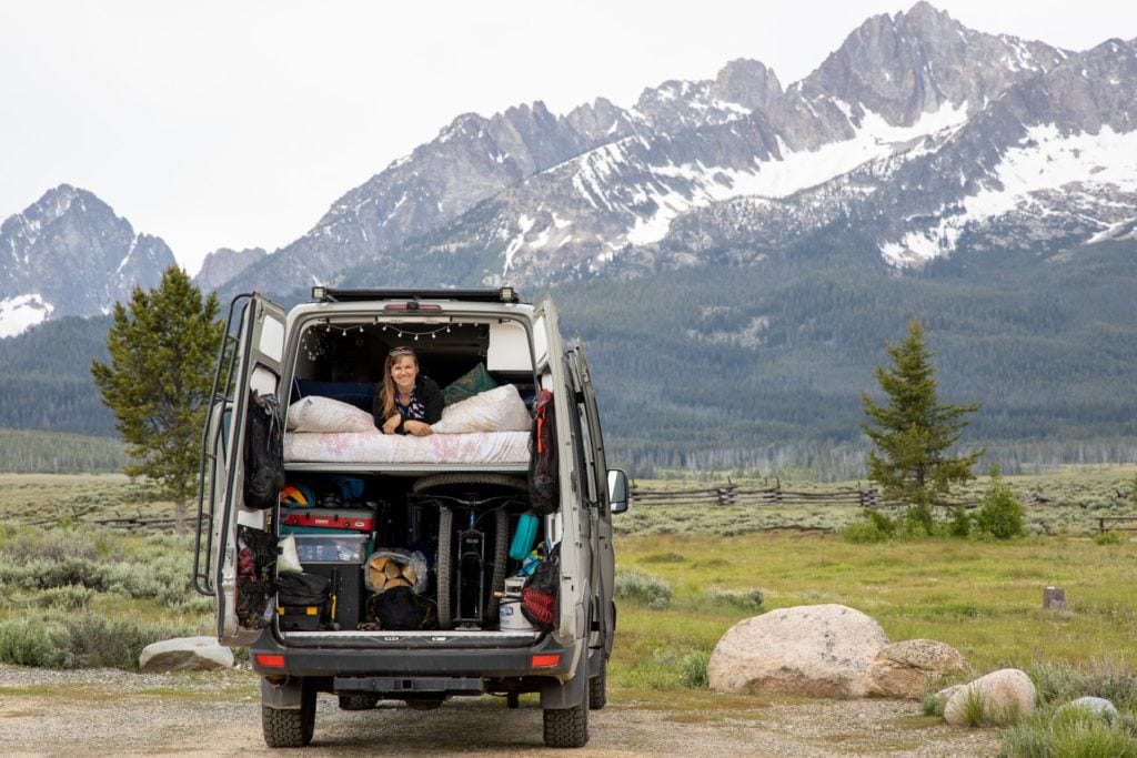 Kristen looking out the back of her converted Sprinter camper van with the Sawtooth mountains in the background