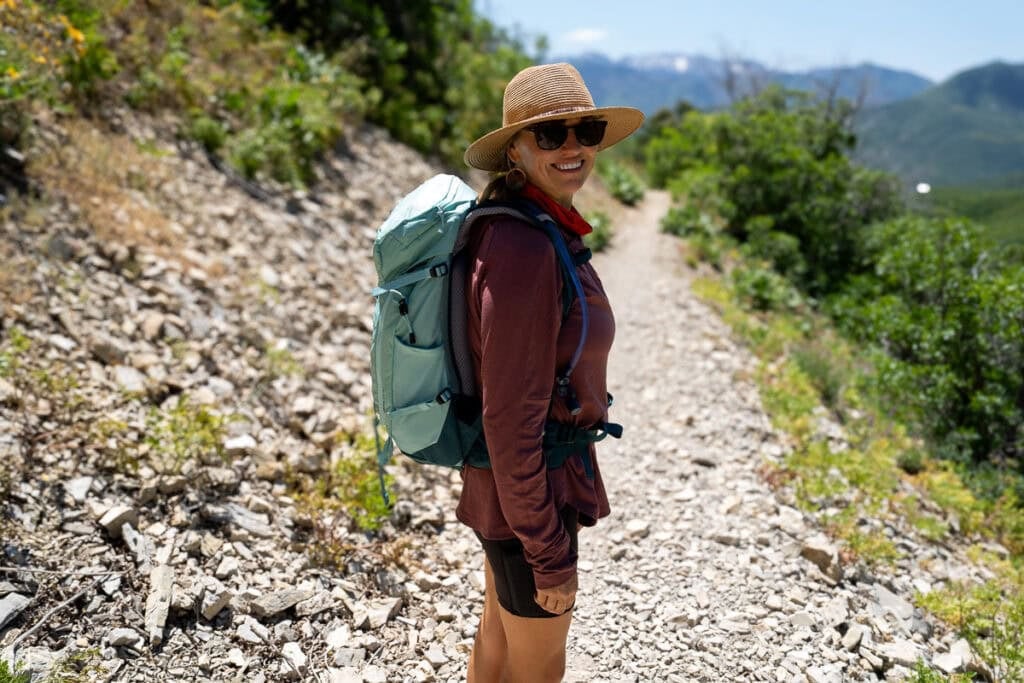 Kristen Bor wearing the Deuter Trail 28 SL backpack on a trail in Park City with green foliage