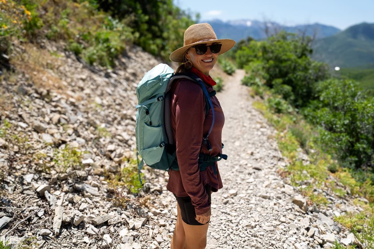 Kristen Bor wearing the Deuter Trail 28 SL backpack on a trail in Park City with green foliage