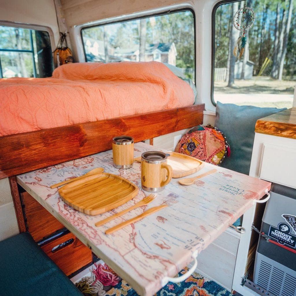 a closeup on a slider table from under a bed in a campervan with cutlery for two