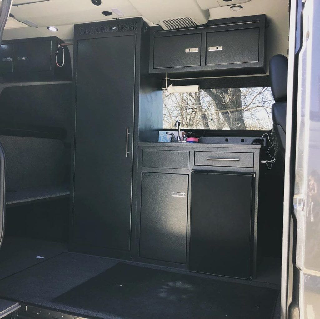 the interior of a campervan with black aluminum cabinets